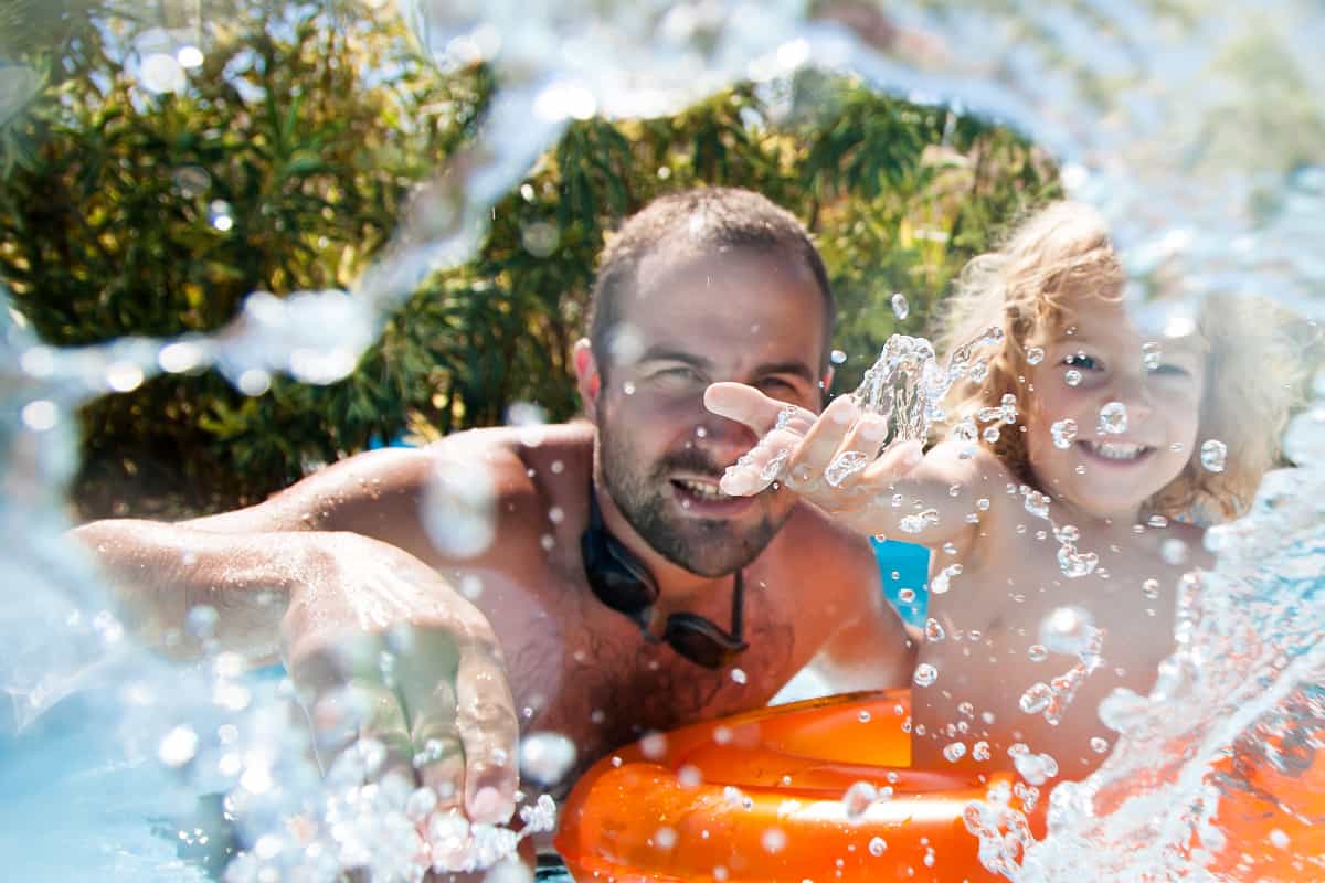 father and child playing in pool father and child playing in pool